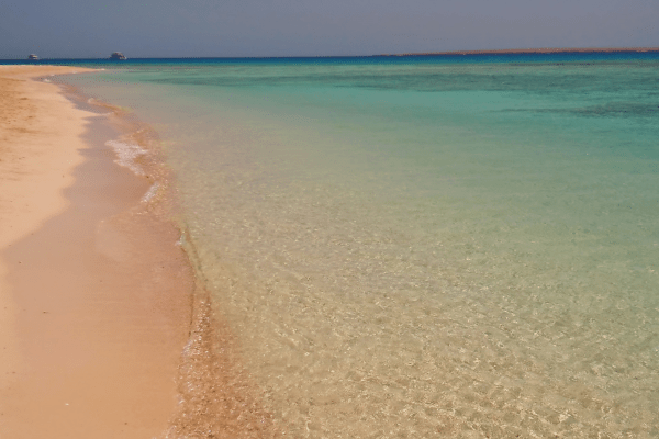 Tranquil beach with clear water and golden sand.