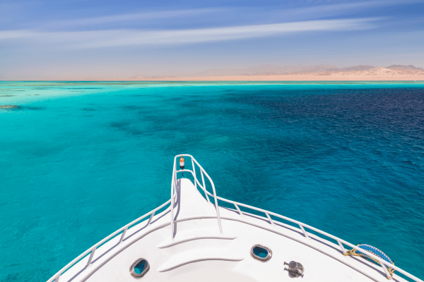Bow of boat overlooking clear turquoise sea and horizon.
