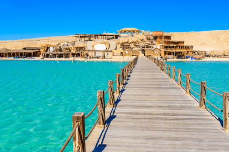Wooden pier leading to beach resort on sunny day.