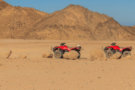 ATVs parked in desert landscape with mountains.