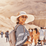 Smiling traveler in a sun hat at the Valley of the Kings in Egypt, surrounded by a group of Discovery Tours Egypt tourists, exploring ancient wonders.