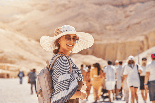 Smiling traveler in a sun hat at the Valley of the Kings in Egypt, surrounded by a group of Discovery Tours Egypt tourists, exploring ancient wonders.
