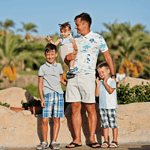 Family posing together in a sunny location in Egypt, with palm trees in the background.
