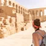 Woman exploring ancient sunlit temple ruins.