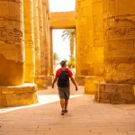 Visitor walking through ancient columns at the Karnak Temple complex in Luxor, Egypt, experiencing the grandeur of Egyptian history with Discovery Tours Egypt.