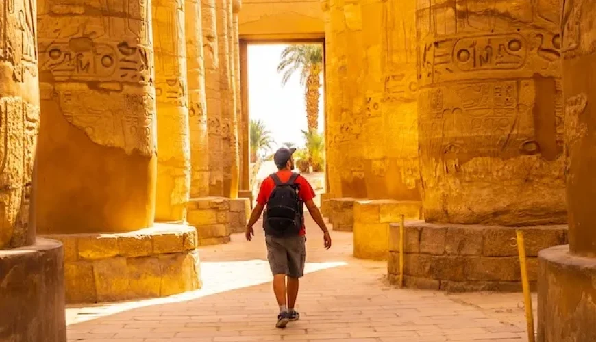 Visitor walking through ancient columns at the Karnak Temple complex in Luxor, Egypt, experiencing the grandeur of Egyptian history with Discovery Tours Egypt.