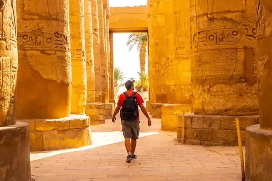 Visitor walking through ancient columns at the Karnak Temple complex in Luxor, Egypt, experiencing the grandeur of Egyptian history with Discovery Tours Egypt.