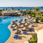 Beautiful resort pool area with beach umbrellas and sun loungers overlooking the Red Sea in Egypt.
