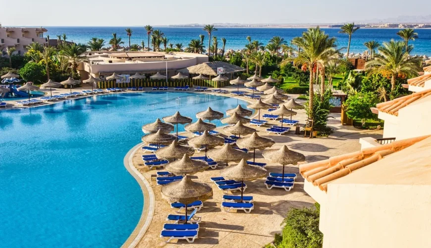 Beautiful resort pool area with beach umbrellas and sun loungers overlooking the Red Sea in Egypt.