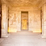 Interior view of an ancient Egyptian temple with hieroglyphics and carved pillars.