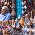 Man beside colourful ceramic wares at market.