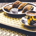 Samosas with chutney on ornate tray.