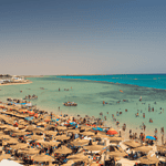 Crowded beach, turquoise water, boats, temporary shelters