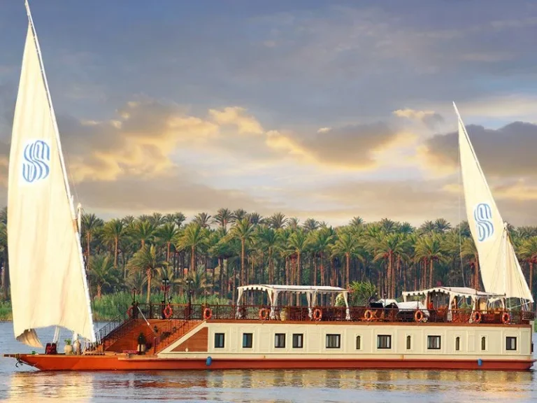 Fantastic Sonesta Dahabiya cruise sailing by tropical palm tree, cruising along with Nile River, inspired by Discovery Tours Egypt.