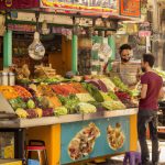 Colourful spice market stall with customer and vendor.