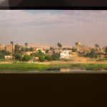 Rural landscape with river and buildings through window.